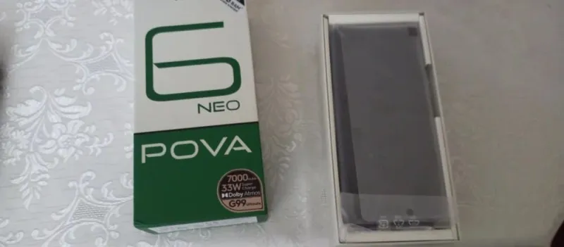 Коробка смартфона Tecno Pova 6 Neo, на которой указаны характеристики (7000 мАч, 33 Вт, G99), рядом с самим телефоном в заводской упаковке.