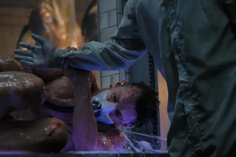 В футуристической лаборатории обнаженного мокрого мужчину с маской на лице, подключенного к аппаратам, приводят в чувство в новом теле (оболочке).