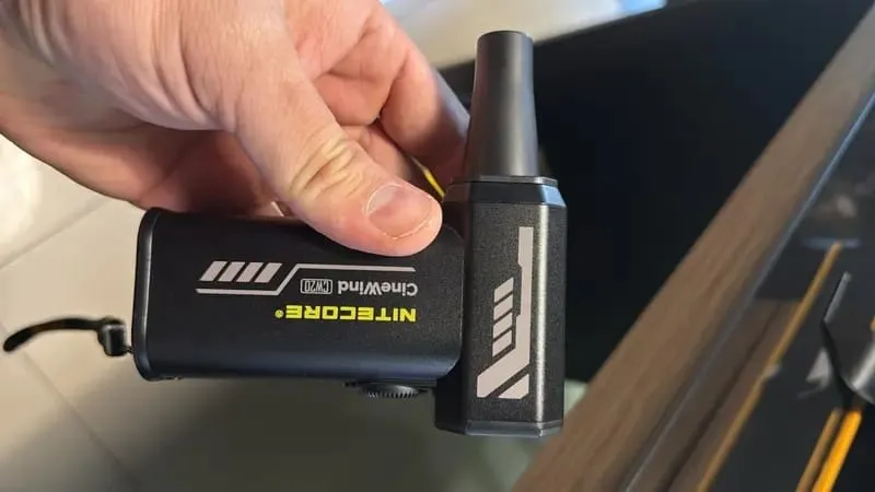 Демонстрация компактности: Nitecore CW20 с установленной насадкой в руке, вид сбоку, показывающий эргономику устройства.