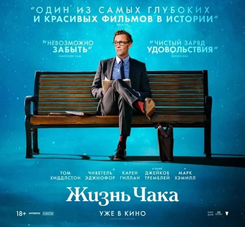 Том Хиддлстон в деловом костюме стоит посреди пустой улицы